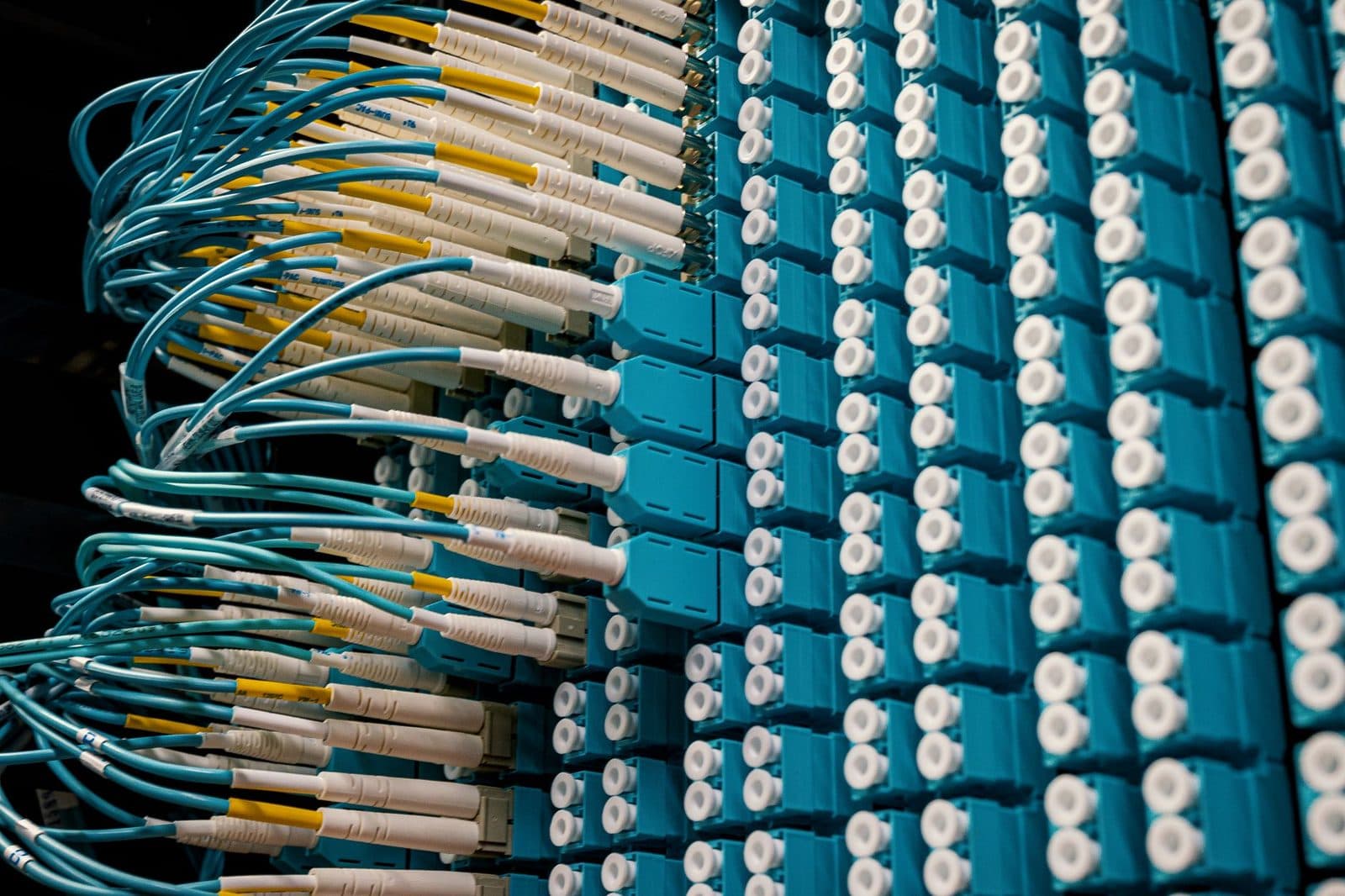 Pannello di permutazione ottica con cavi turchese e connettori LC collegati in un locale tecnico