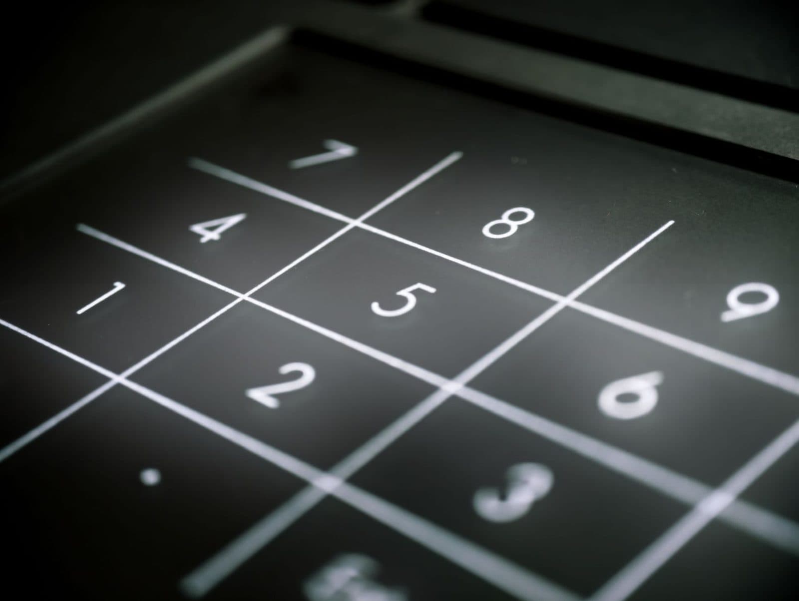 Gros plan sur un clavier numérique noir rétroéclairé avec les chiffres 1 à 9 d'un appareil de bureau