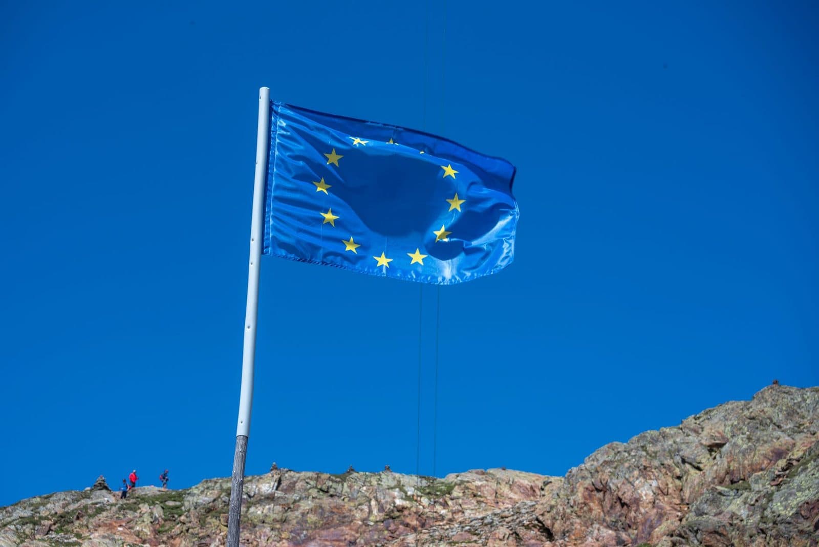 Drapeau de l'Union européenne flottant sur un mât au sommet d'un rocher, sous un ciel bleu