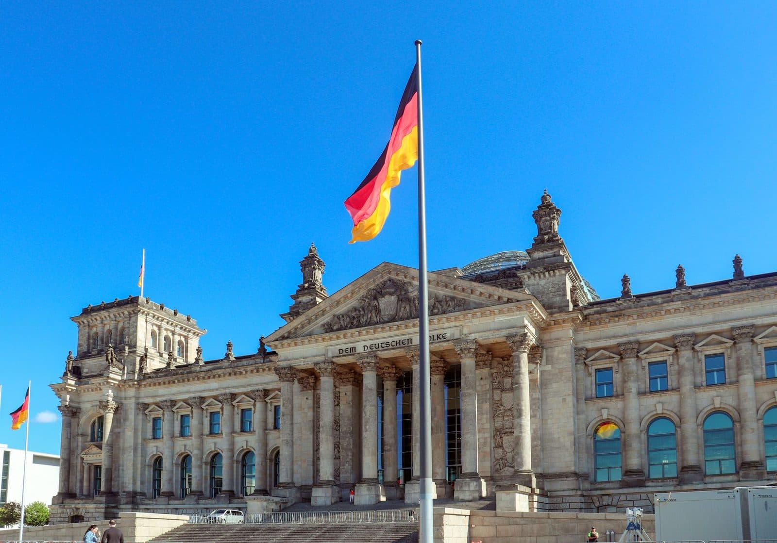 Facade of the Reichstag in Berlin with the German flag flying against a blue sky