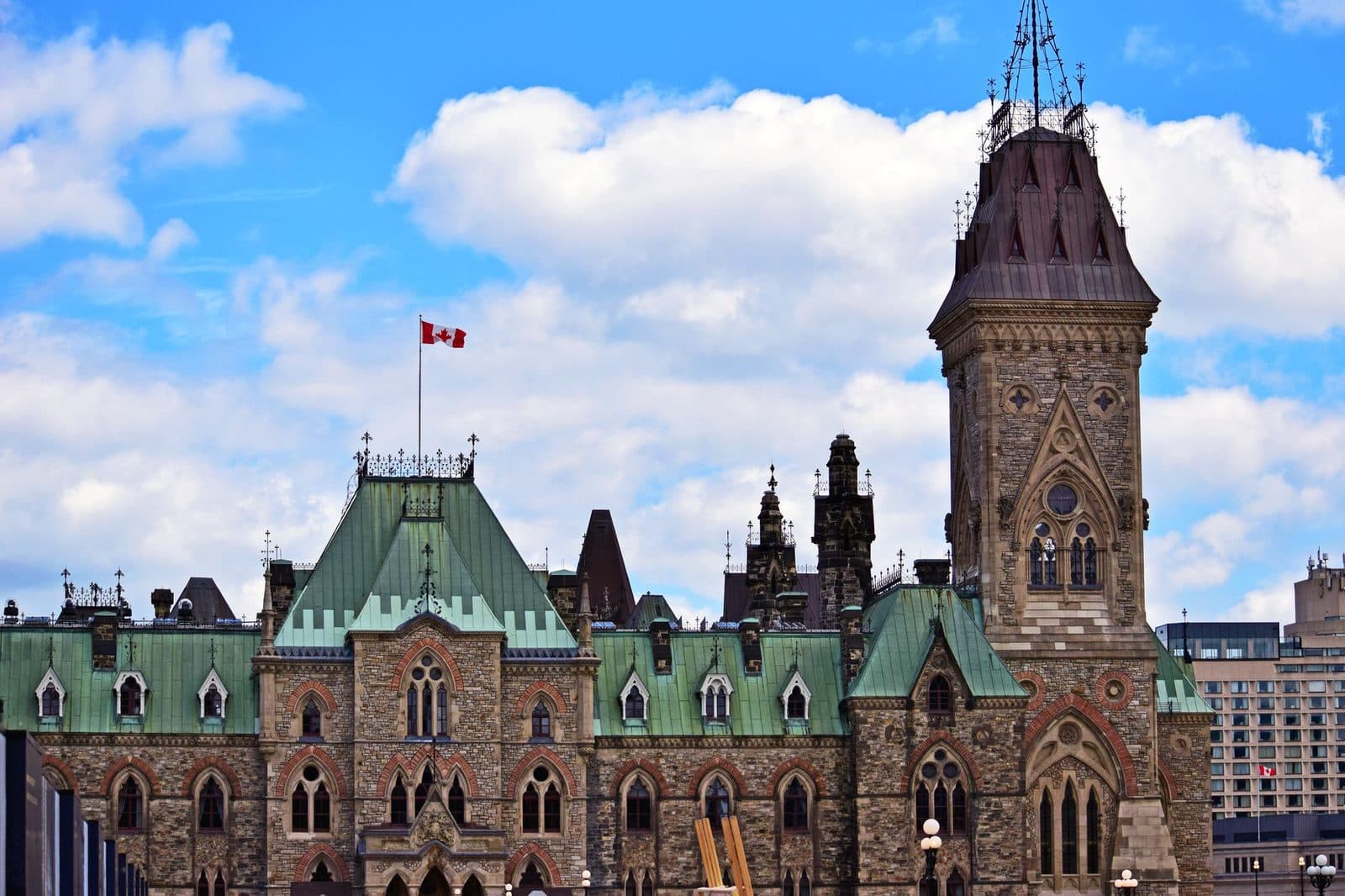 Edificio Ovest del Parlamento canadese a Ottawa, bandiera del Canada che sventola sotto un cielo nuvoloso