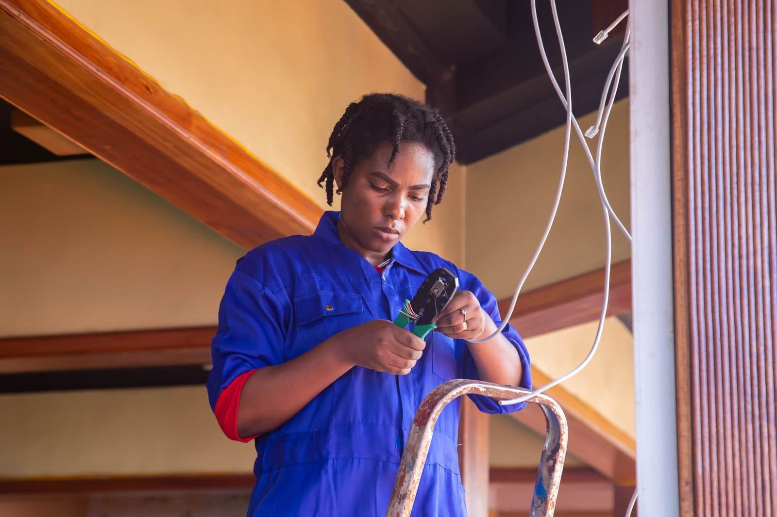 Técnica con mono azul pelando un cable telefónico con unos alicates durante una instalación