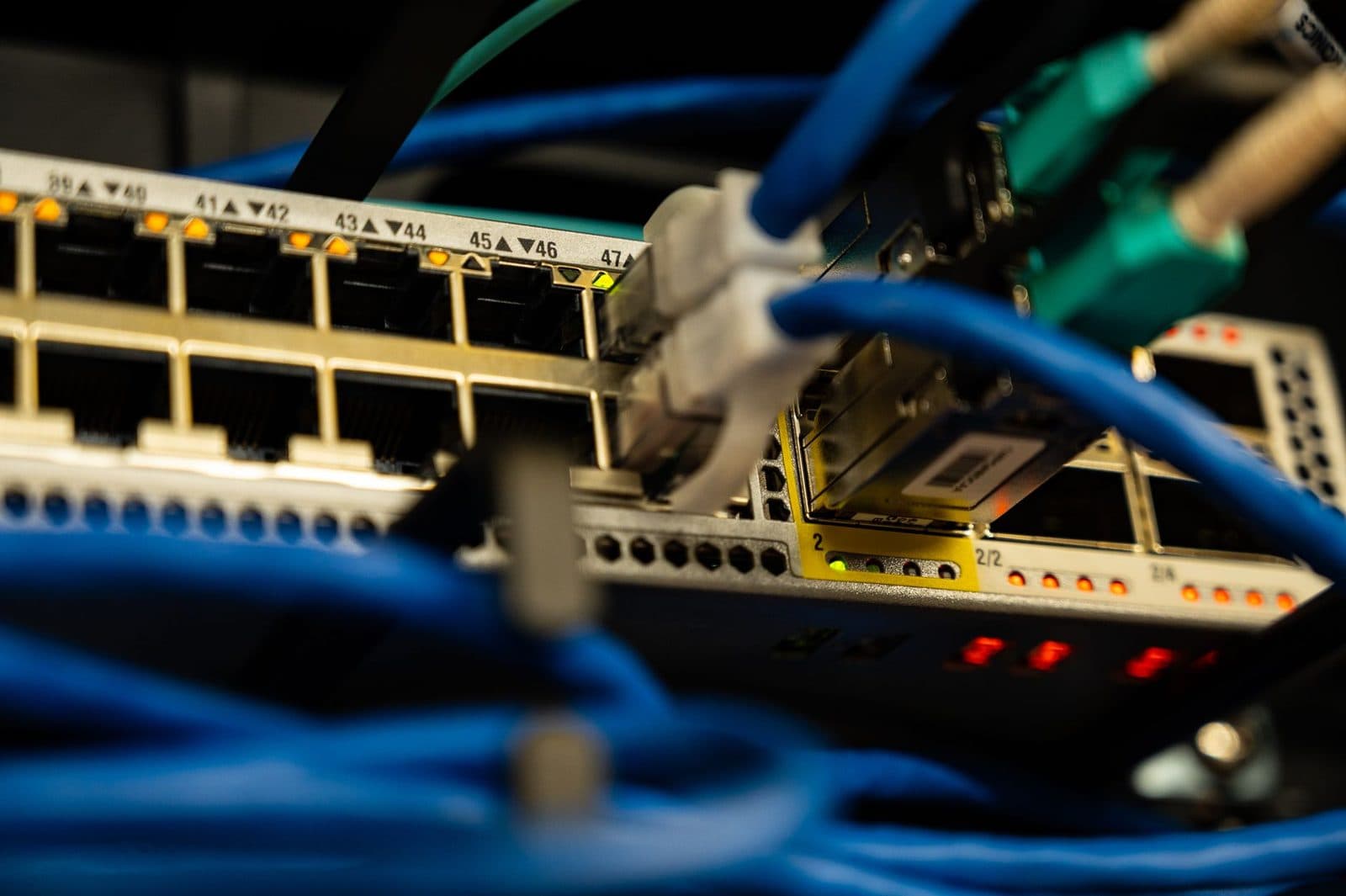 Gros plan sur un switch réseau avec ports RJ45 numérotés, câbles Ethernet bleus et voyants allumés