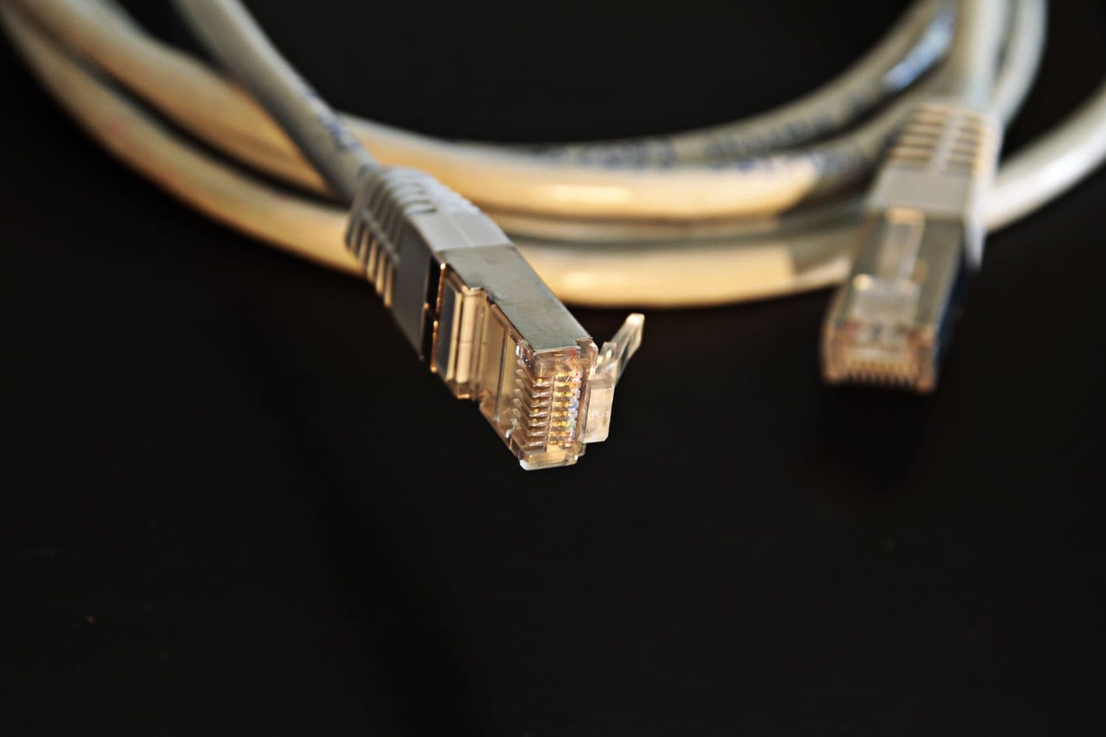 كابلان شبكة إيثرنت بموصلات RJ45 ملفوفان على خلفية سوداء