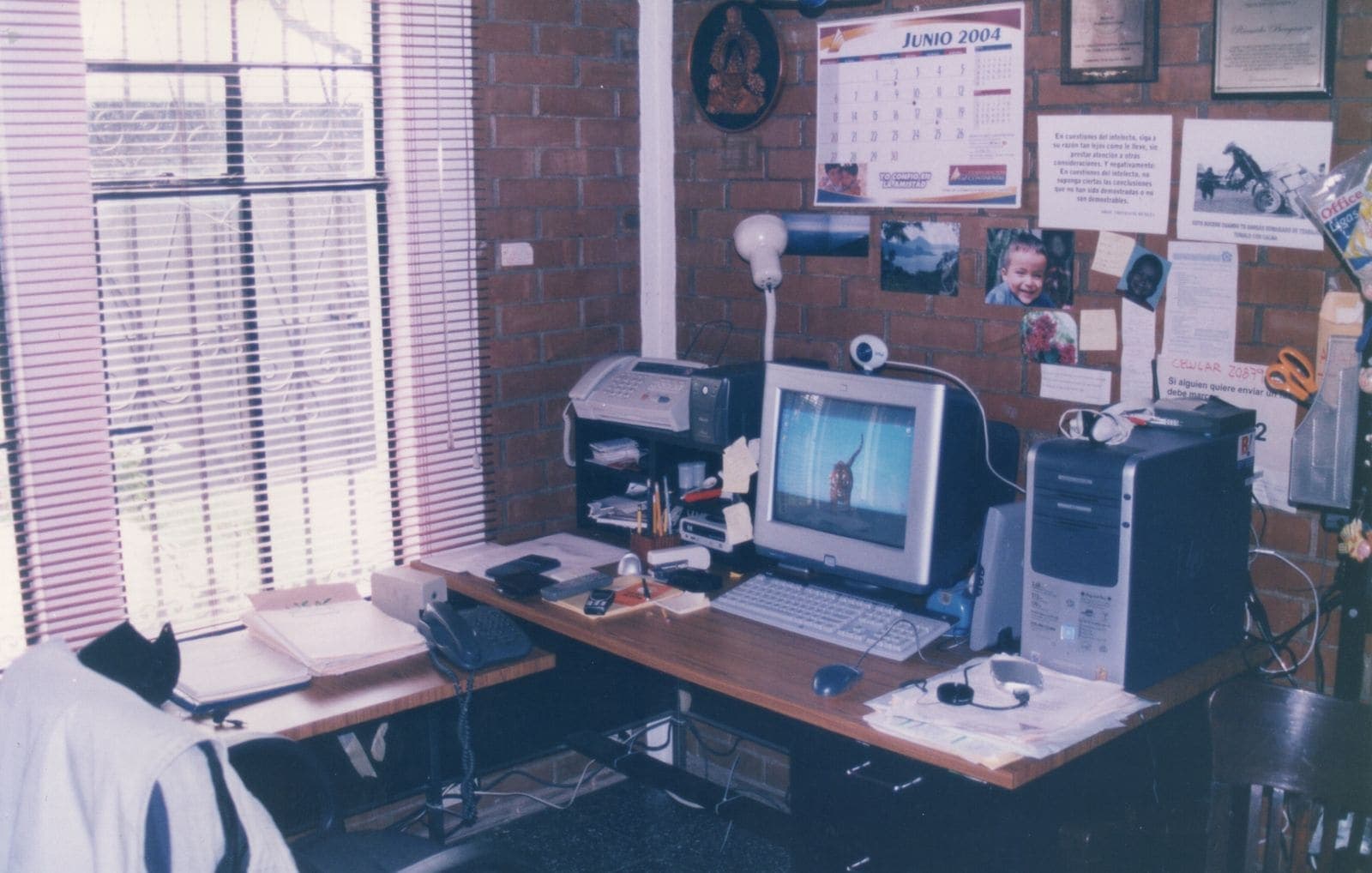 Office with a fax-printer, a landline telephone and an old computer in front of a brick wall