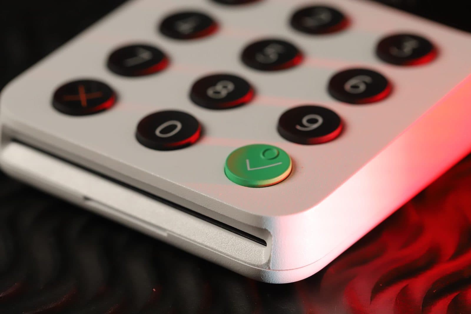 Primer plano del teclado numérico blanco de un aparato tipo fax con teclas negras y botón verde