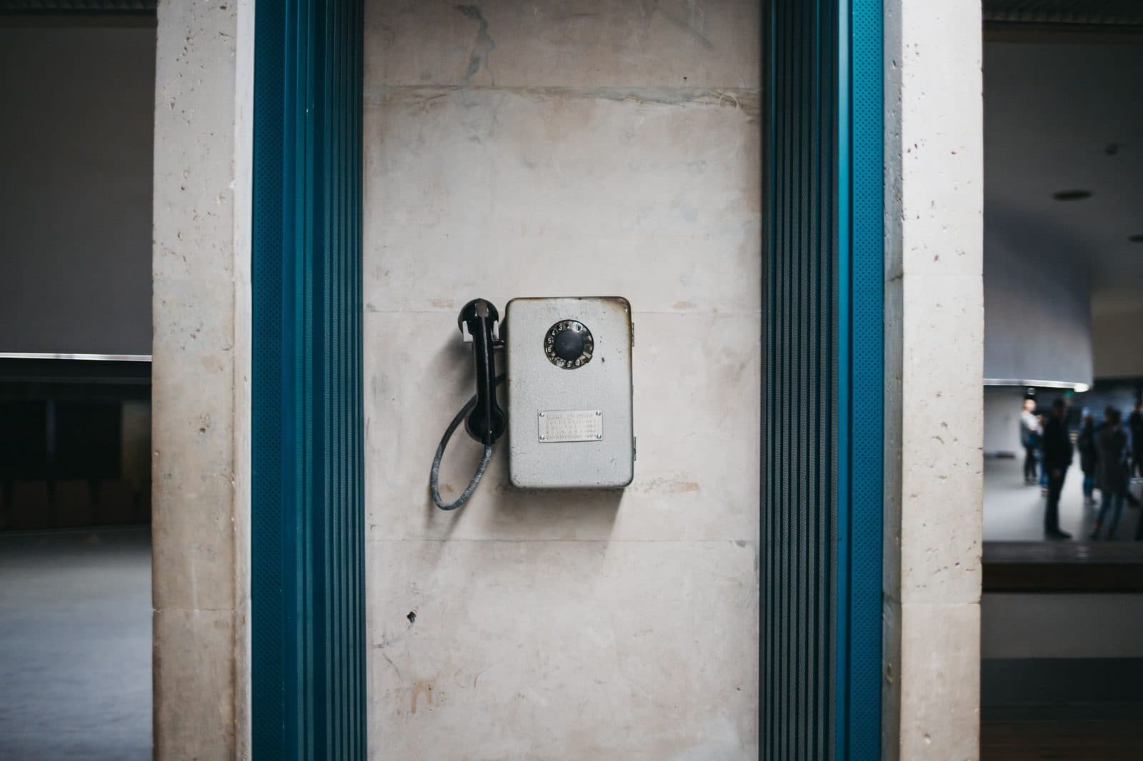 Altes Wandtelefon mit Wählscheibe, befestigt an einer Steinsäule in einer öffentlichen Halle